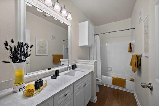 A bathroom with a white counter top and a white sink.