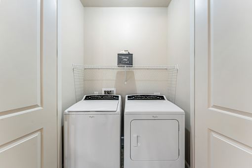 Two white front loading washing machines in a laundry room.