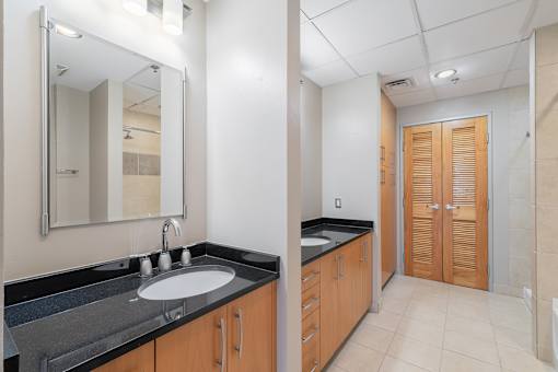 A bathroom with a sink, mirror, and wooden cabinets.