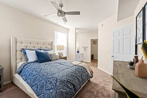 A bedroom with a large bed and a ceiling fan.