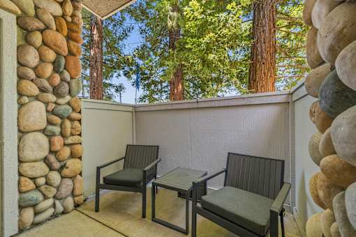 Two chairs and a table are on a patio.