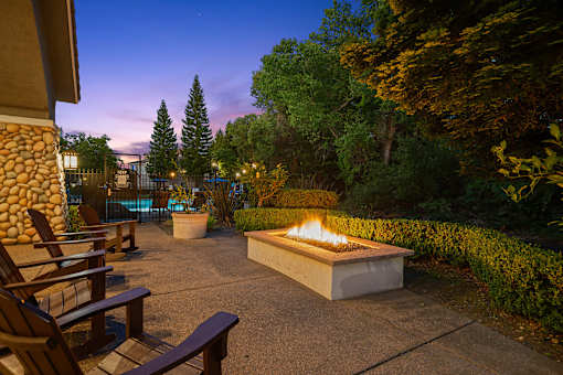 A fire pit in the middle of a patio surrounded by chairs.