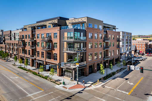 A street view of a city with apartment buildings on the corner.