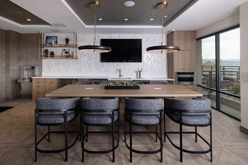 A modern kitchen with a long wooden table and grey chairs.
