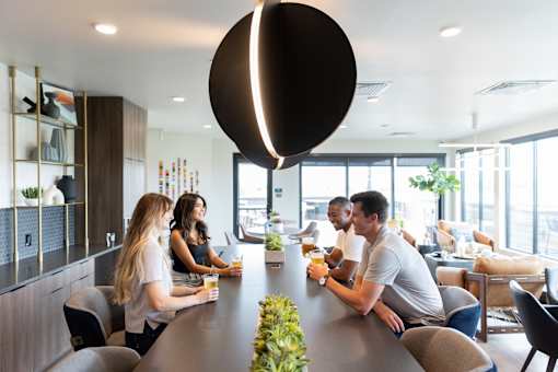 A group of people are sitting around a long table in a modern room.