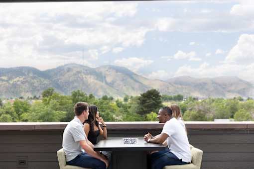 Three people sitting at a table with a mountainous landscape in the background.