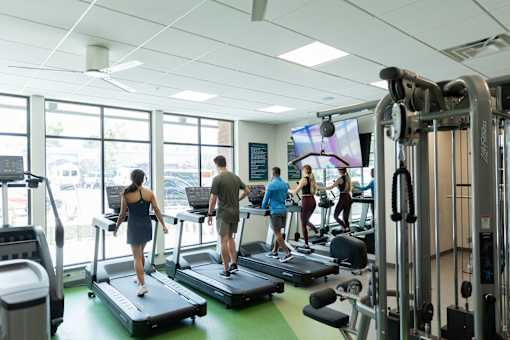 A gym with people exercising and a TV screen.