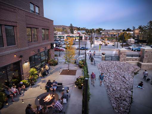 A group of people are gathered around a fire pit in a courtyard.