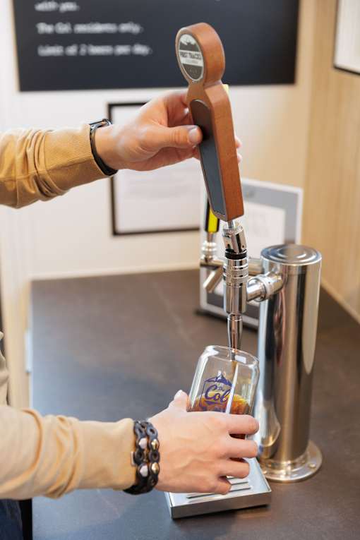 A person is pouring a beer from a tap into a glass.