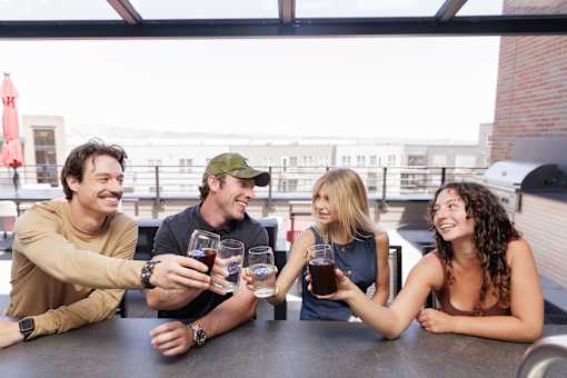 Four people toasting with drinks at a table.