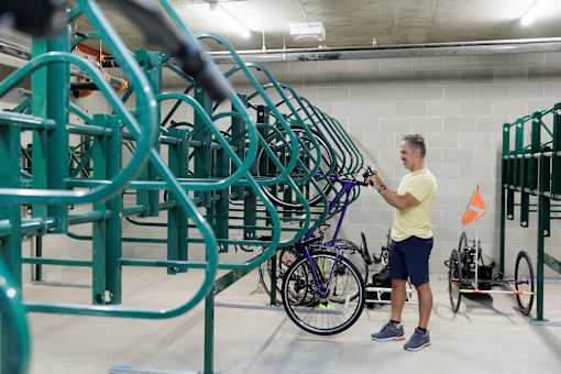 A man in a yellow shirt is standing in a bike storage area.