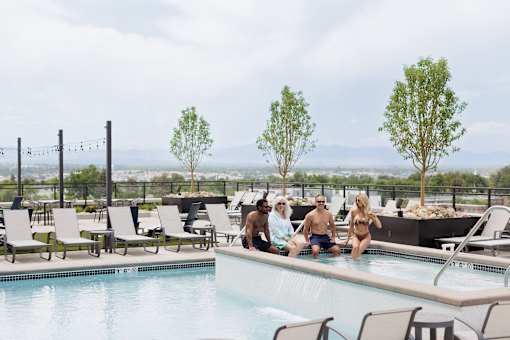 A group of people are sitting by a pool on a sunny day.