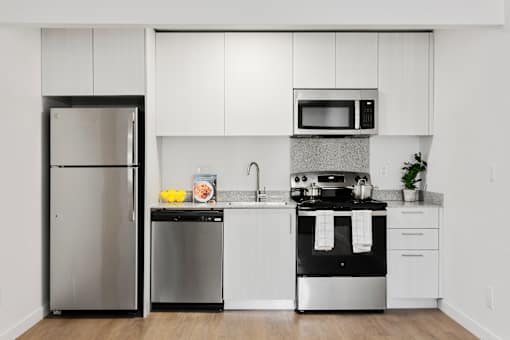 A modern kitchen with white cabinets and stainless steel appliances.