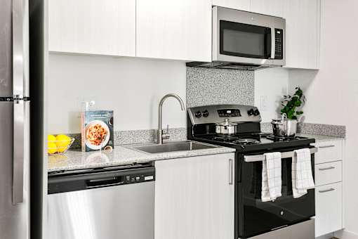 A modern kitchen with a black stove top oven and white cabinets.