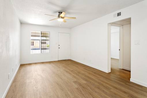 A room with a ceiling fan and a window with blinds.