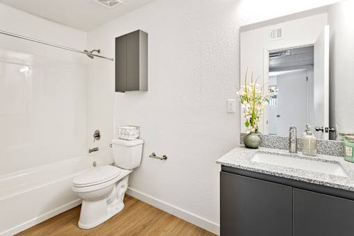 A white toilet sits in a bathroom next to a sink.