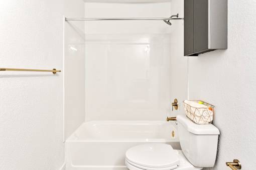 A white toilet sits next to a bathtub in a bathroom.
