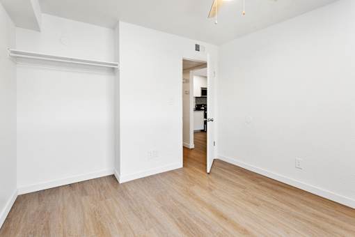 A white room with a sliding door and wooden flooring.