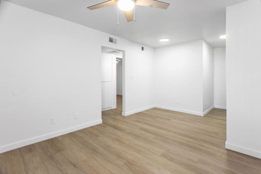 an empty living room with white walls and a ceiling fan