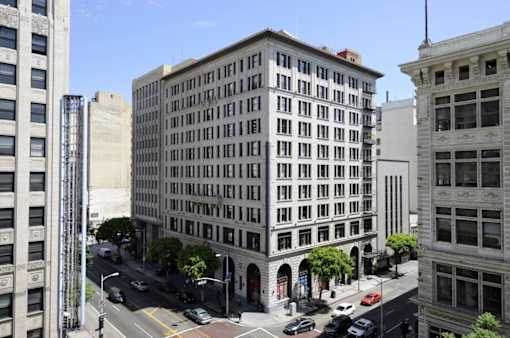 A street view of a city with a large building in the middle.