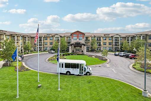 A white bus is parked in front of a building with a flag on a pole.