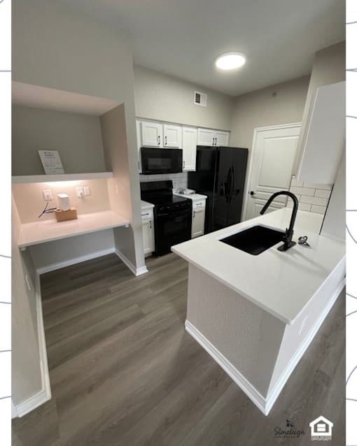 A kitchen with a black fridge and white countertops.