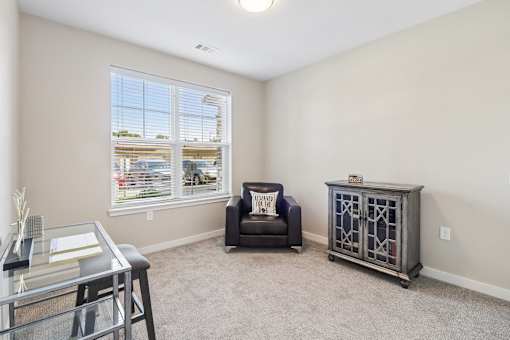 A living room with a black chair and a glass coffee table.