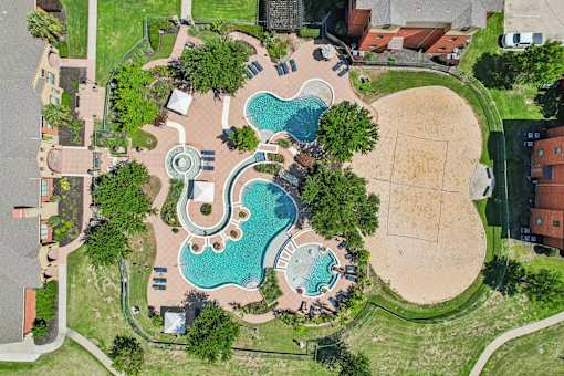 An aerial view of a park with a swimming pool and a sandy area.