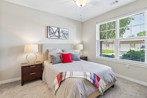 A bedroom with a bed, two lamps, and a ceiling fan.