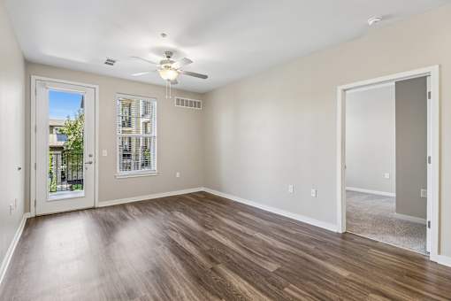A room with a ceiling fan and a window with a view of a balcony.