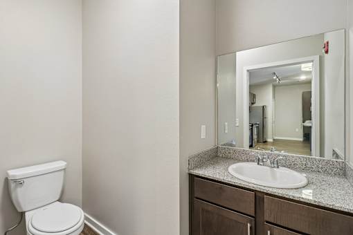 A bathroom with a toilet, sink and mirror.