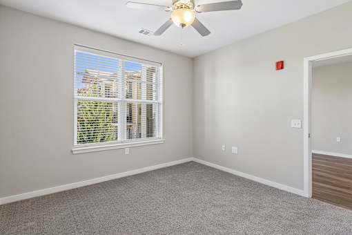 A room with a ceiling fan and a window with blinds.