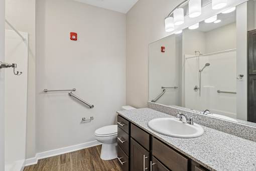 A white toilet sits in a bathroom with a sink and mirror.