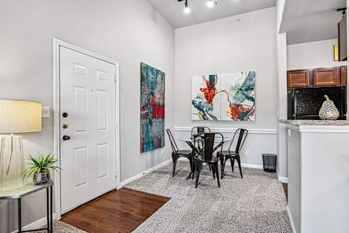 A white door is in a room with a painting on the wall and a table with chairs.