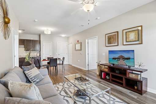 A living room with a grey couch and a television on a wooden stand.
