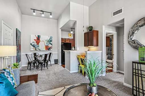 A living room with a grey sofa, a dining table and a painting on the wall.