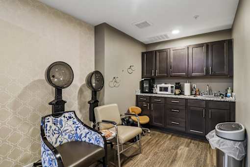A room with a chair and a table with a clock on the wall.