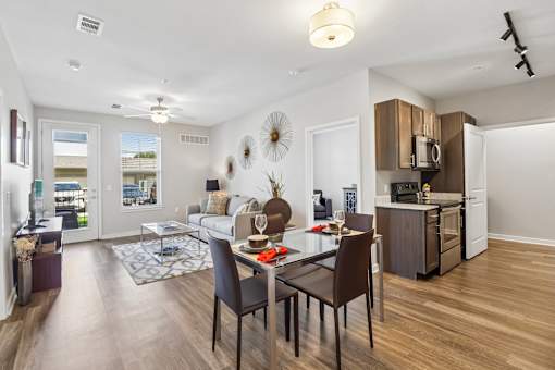 A modern kitchen and dining area with dark wood floors and furniture.