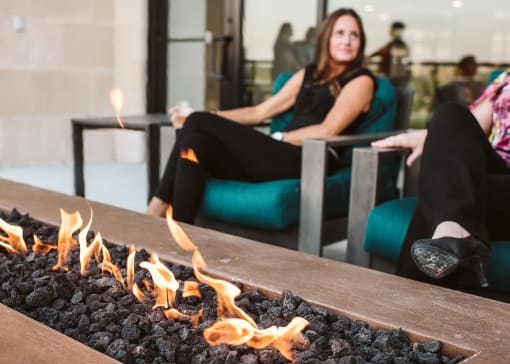 two women sitting oudoors in lounge chairs around a fire pit table at The Apex at CityPlace, Overland Park, KS