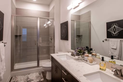 bathroom with a shower and double vanity at The Apex at CityPlace, Overland Park