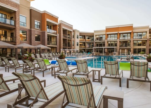 Rows of chaise lounge chairs around an outdoor pool surrounded by apartment buildings at The Apex at CityPlace, Kansas, 66210
