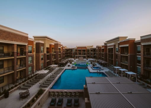 view of u shaped apartment complex with an outdoor pool in the center and rows of seating on the patio at The Apex at CityPlace, Kansas