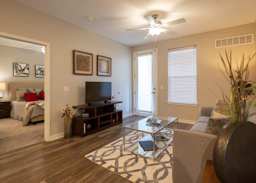 A furnished living room with a ceiling fan and patio access in a 2-bedroom apartment at Aspen Ridge 55+ Apartment Community.