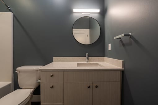 A bathroom with a toilet, sink, and mirror.
