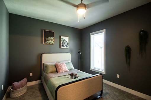 A bedroom with a bed, a ceiling fan, and two wall art pieces.