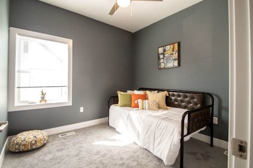 A bedroom with a bed, pillows, and a window.