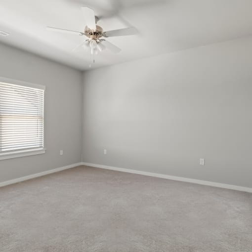 an empty room with a ceiling fan and a window at Hillcrest Village, Springdale, AR