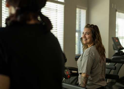 A woman with a tattoo on her arm is standing in a gym.