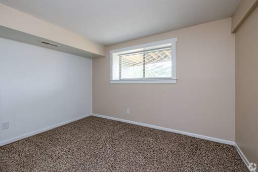 A room with a window and carpeted floor.