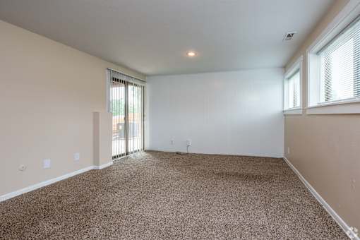 A spacious room with carpeted floor and sliding glass doors.